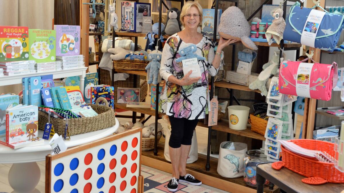 Susan Dawson, store manager of Sur La Mer Coastal Goods, shows items for sale in the kids' section.