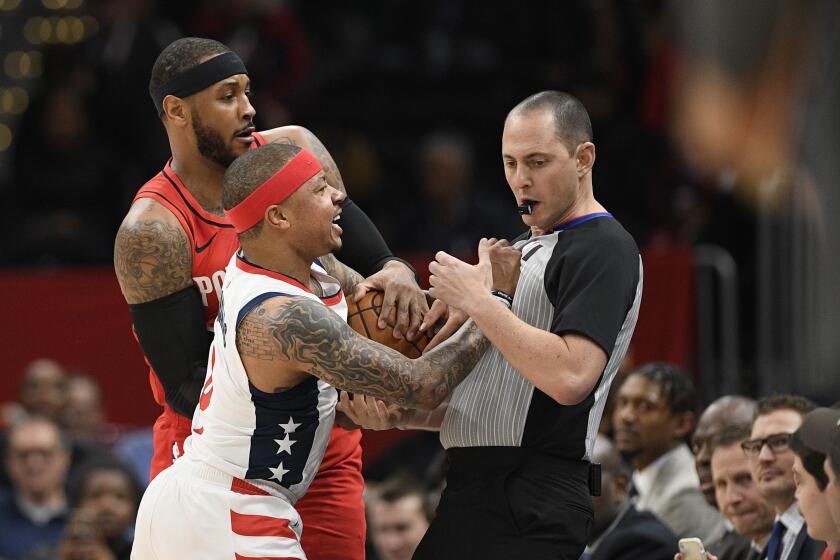 Washington Wizards guard Isaiah Thomas (4) comes in contact with referee Marat Kogut, right, next to Portland Trail Blazers forward Carmelo Anthony, back, during the first half of an NBA basketball game, Friday, Jan. 3, 2020, in Washington. Thomas was ejected from the game. (AP Photo/Nick Wass)