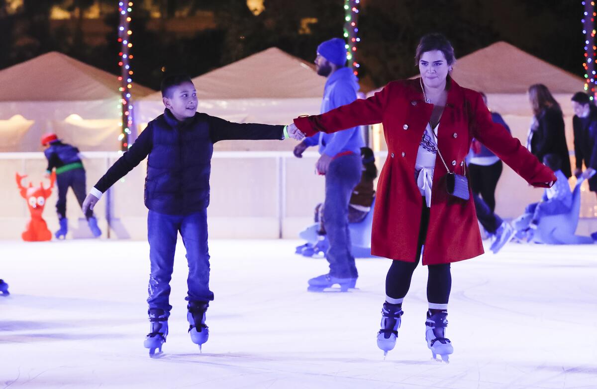 A pair of skaters holds hands at the Santa Ana Winter Village ice-skating in downtown Santa Ana at the Civic Center Plaza. 