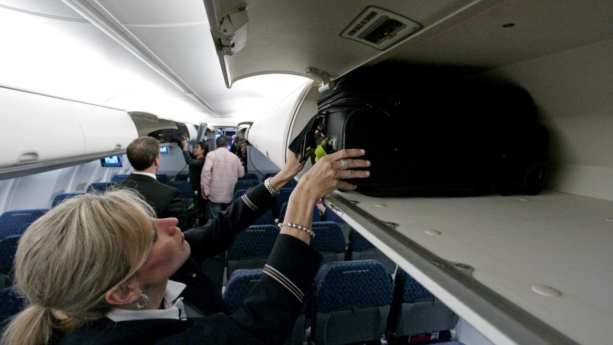American Airlines flight attendant Renee Schexnaildre stows a bag in an overhead bin on a Boeing 737-800 jet at Dallas Fort Worth International Airport. The carrier will allow basic economy fliers one free carry-on bag starting Sept. 5.