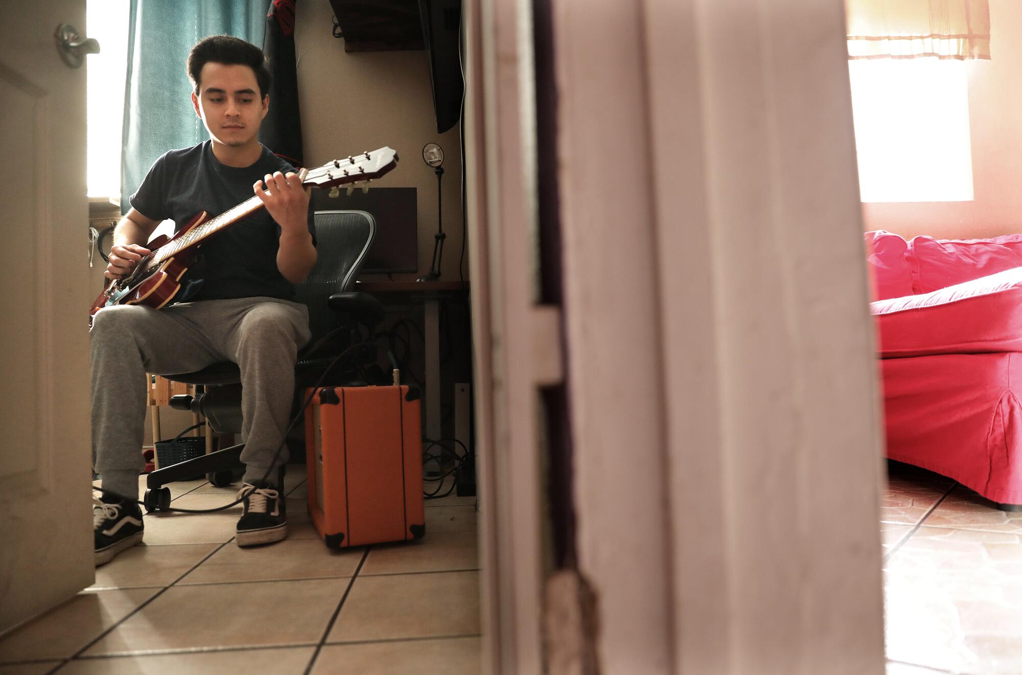 Criztiaan Juarez, 18, plays the guitar at home in Glendale 