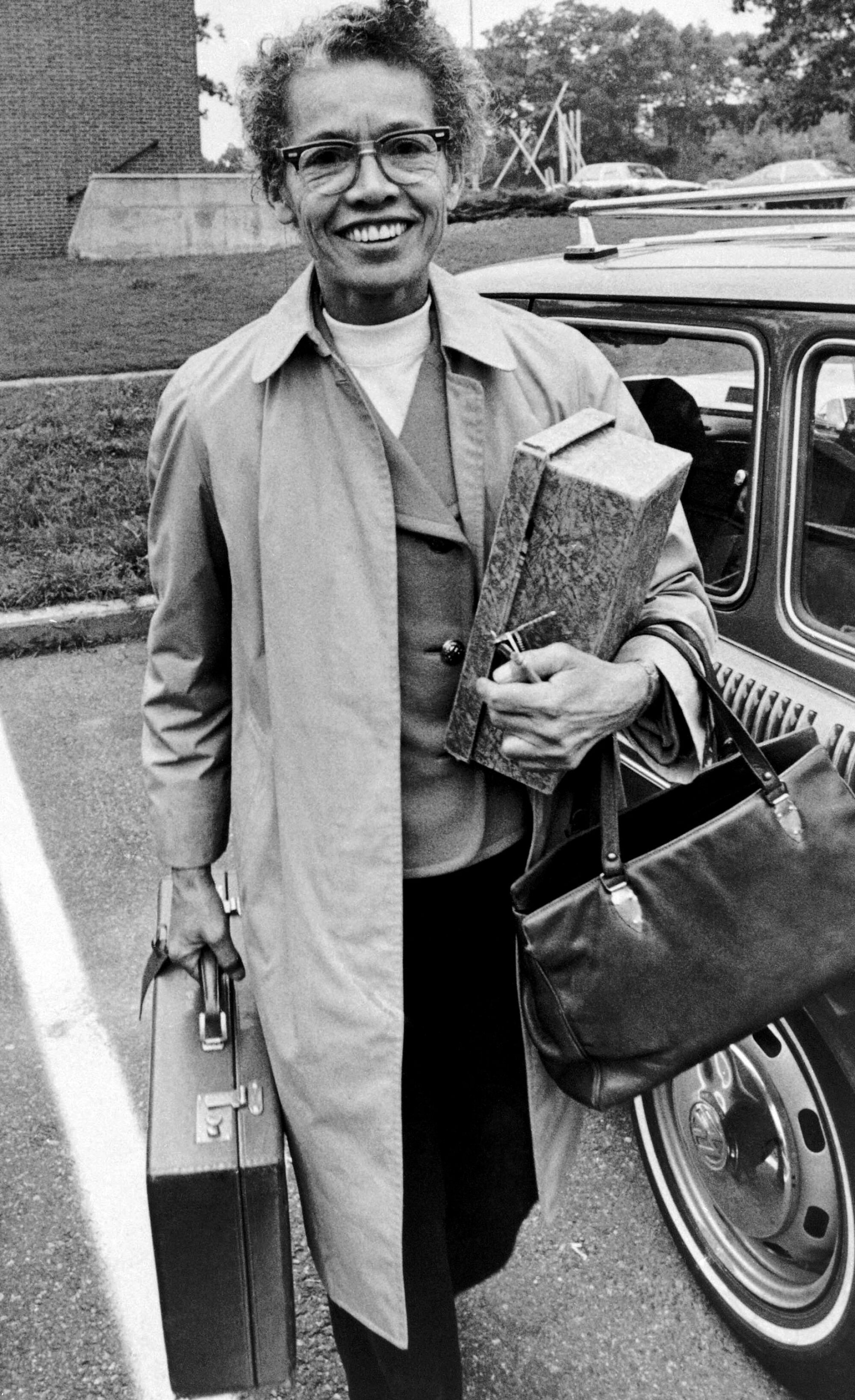 Pauli Murray, in a blazer and overcoat, carries a briefcase. 