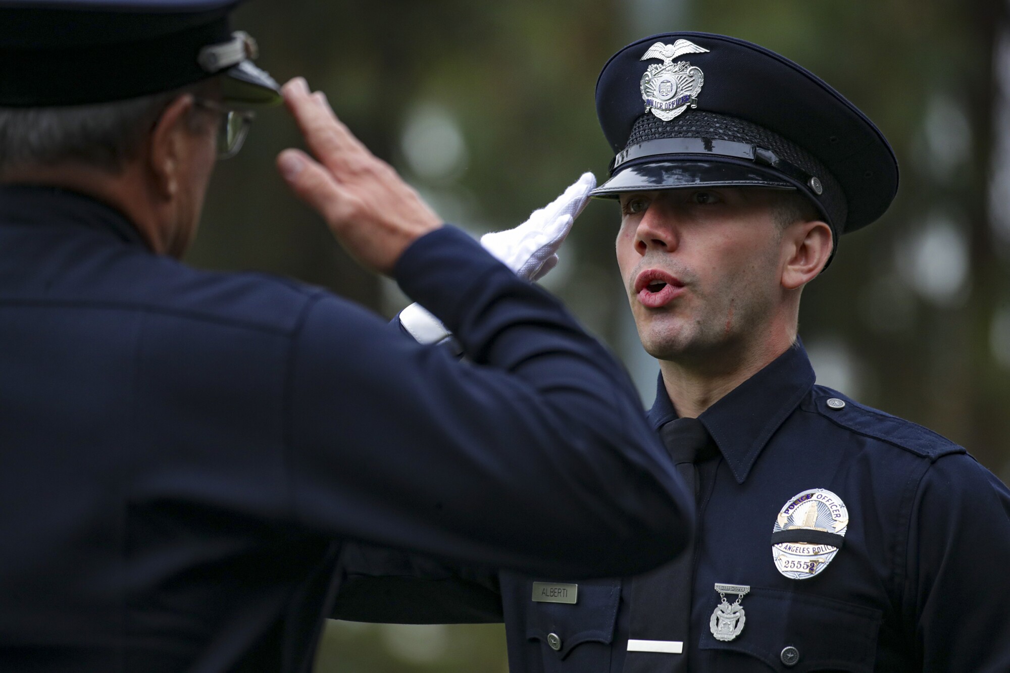 New graduate officer Aaron Alberti, right, salutes LAPD Chief Michel Moore before receiving his diploma.
