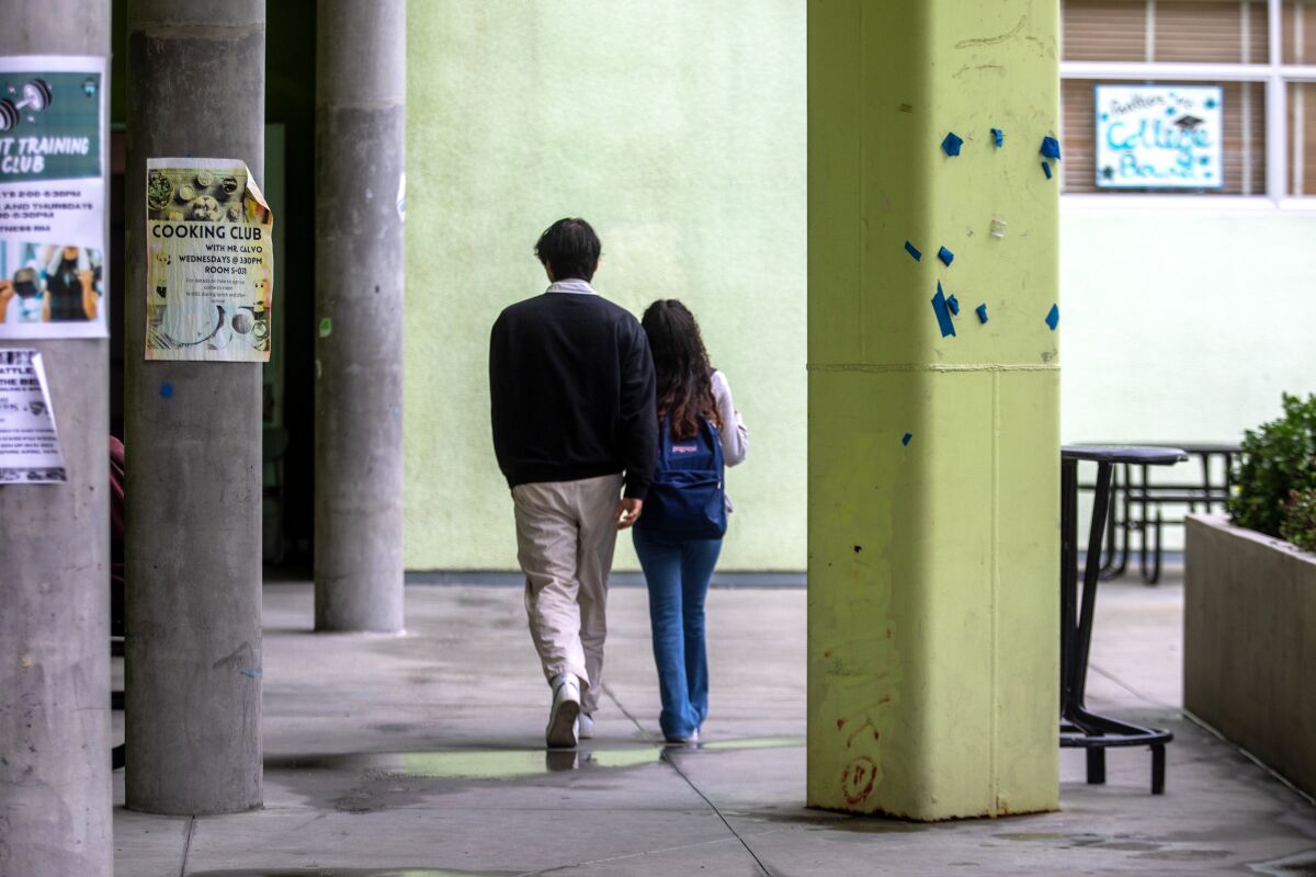 Jonathan Cornejo, trái, và Emily Gramajo, phải, đi bộ đến lớp qua sân trường West Adams Preparatory High School