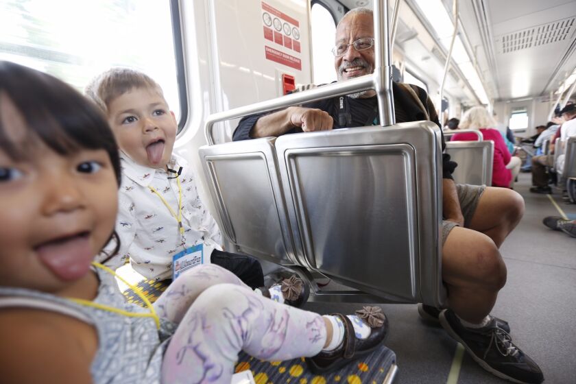 Yuna Minato, 2, left, and Tatsu "Big Engineer" Arai, get playful under the watchful eye of John Wallach, 68, while riding on the first trip on the Metro Expo Line in Culver City on Friday.