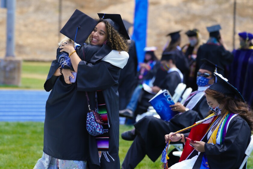 Cal State San Marcos graduates Gabby Garcia, right, and Eliese Holt, both 23, hug at their graduation ceremony on campus.