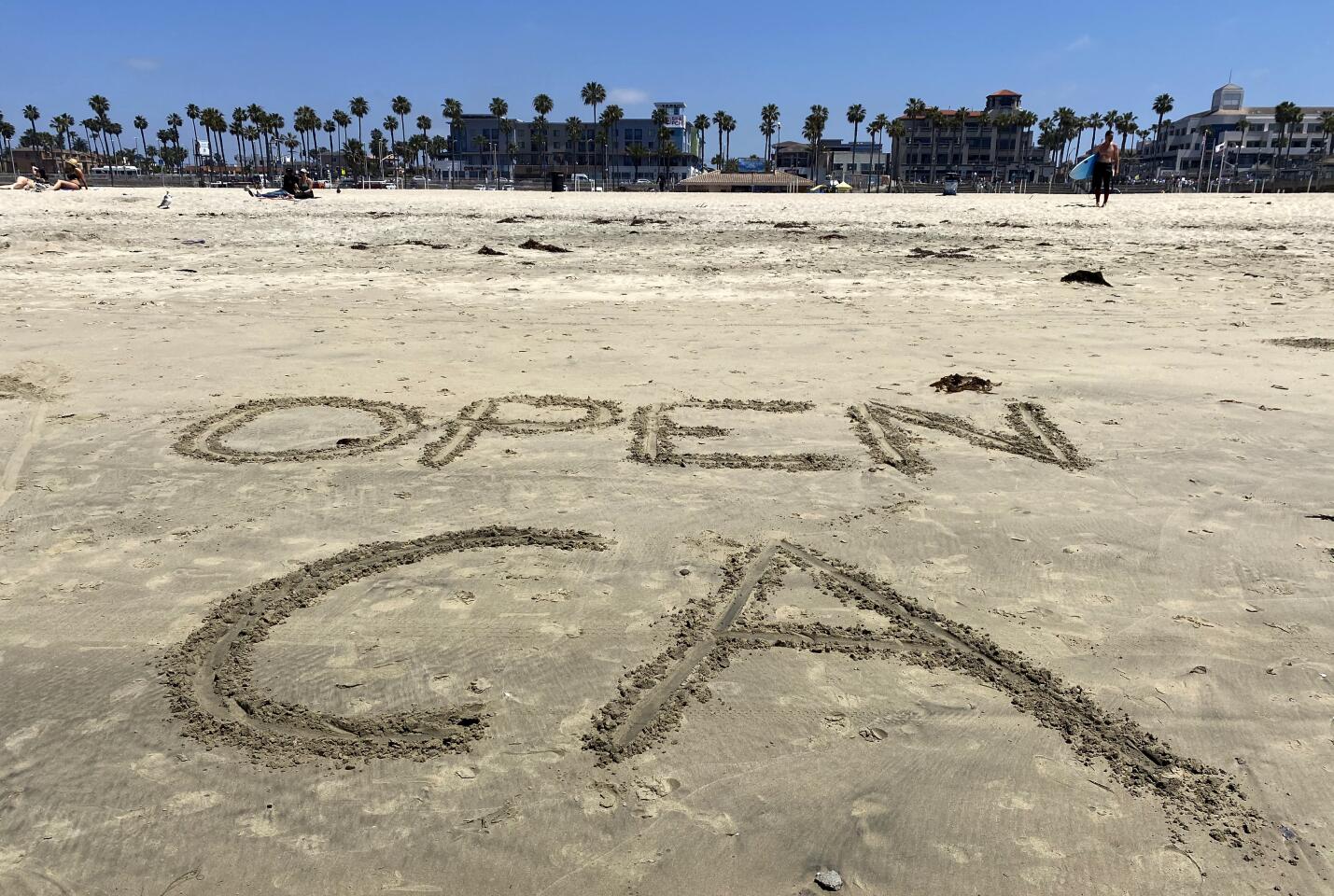 Someone wrote "OPEN CA" on the sand just before the protest in Huntington Beach on Friday.