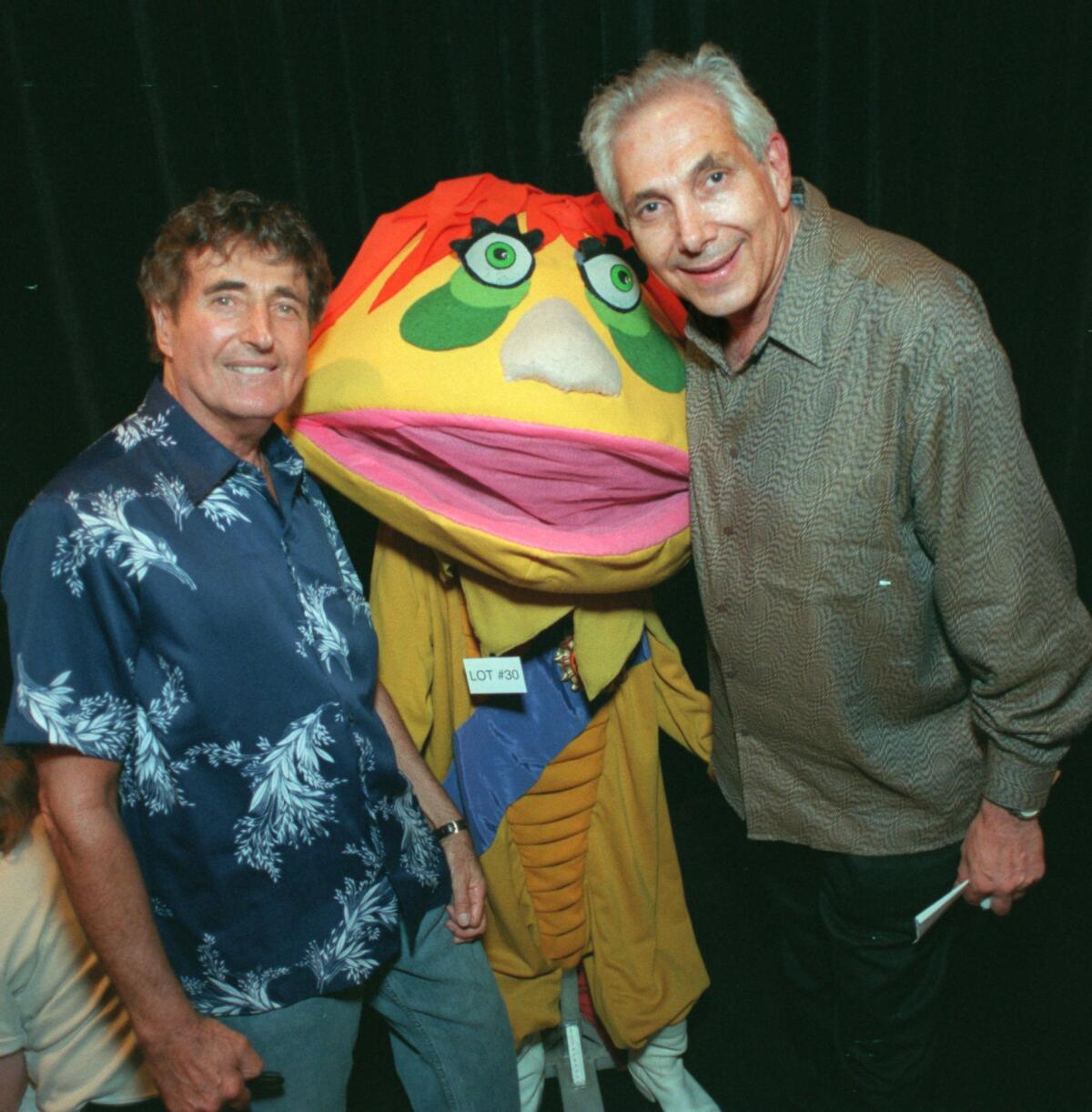 Sid, left, and Marty Krofft stand next to a man dressed as a puppet.