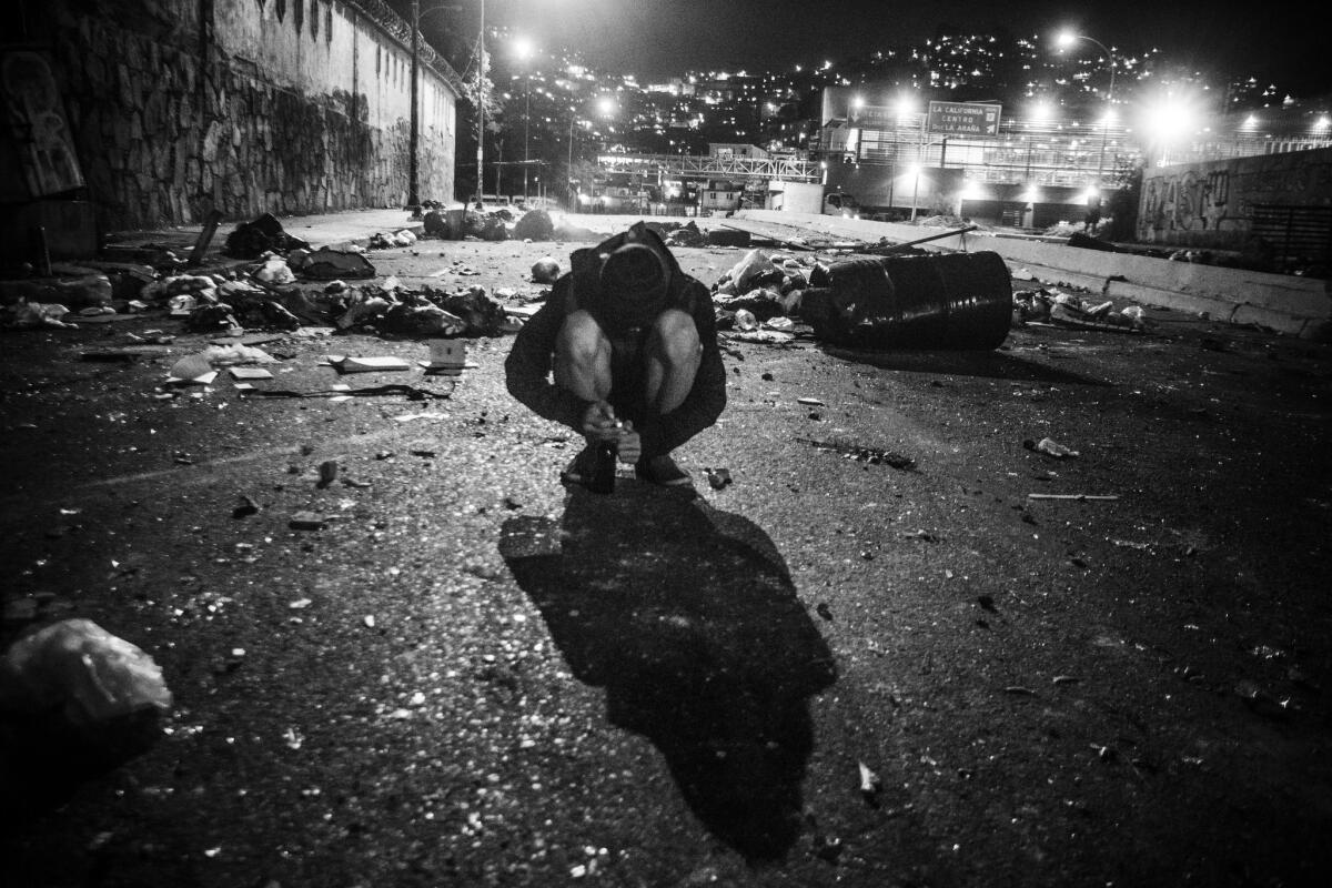 An anti-government protester from Caracas’ La Urbina neighborhood tests a cigarette lighter he will later use to ignite Molotov cocktails. Clashes between authorities and protesters denouncing President Nicolas Maduro happen almost daily.