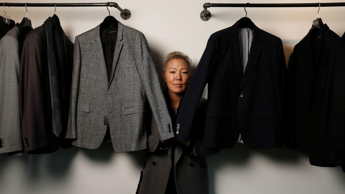 Stylist Jeanne Yang stands with a rack of clothes.