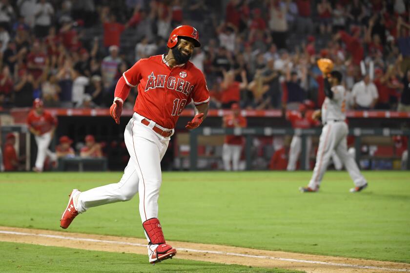 Los Angeles Angels' Brian Goodwin, left, rounds first after hitting a solo home run as Baltimore Orioles relief pitcher Mychal Givens walks off the mound during the ninth inning of a baseball game Thursday, July 25, 2019, in Anaheim, Calif. (AP Photo/Mark J. Terrill)