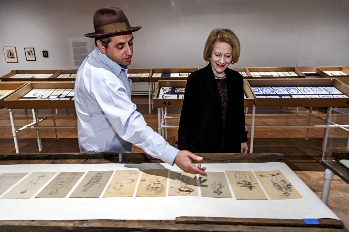 Richard Montoya, with Fowler Museum director Marla Berns, reviewing some of his father's drawings of pachucos on napkins.