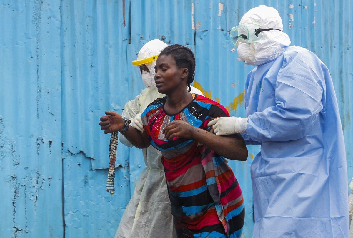 Nurses escort a suspected Ebola patient into a treatment center in Monrovia, Liberia. The CDC says the number of Ebola cases in Liberia and Sierra Leone, the two hardest-hit countries, could reach 550,000 to 1.4 million by late January, if efforts to control the disease aren't stepped up.