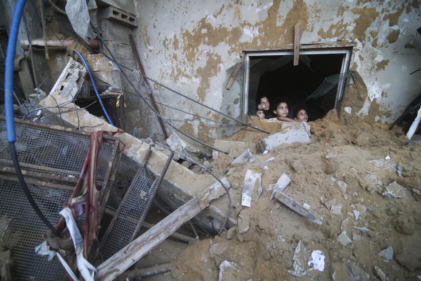 Palestinian children look at the building of the Zanon family, destroyed in Israeli airstrikes in Rafah, Gaza Strip, Saturday, Oct. 14, 2023. (AP Photo/Hatem Ali)