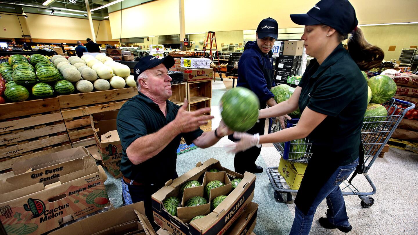 Produce manager Louie Jimenez, left, tosses a watermelon to Ashley Craddock while unpacking melons inside a Haggen grocery store, formerly an Albertsons, in Palmdale. This is the first Haggen grocery store in Los Angeles County.