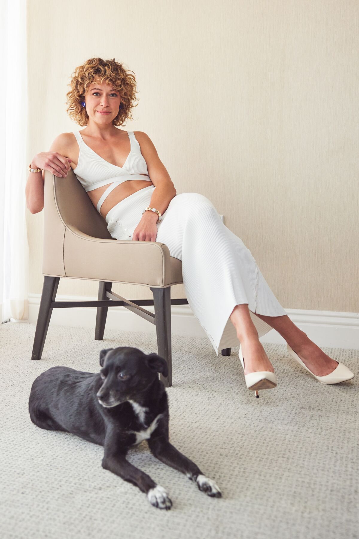 A woman sitting in a chair with a dog by her feet.