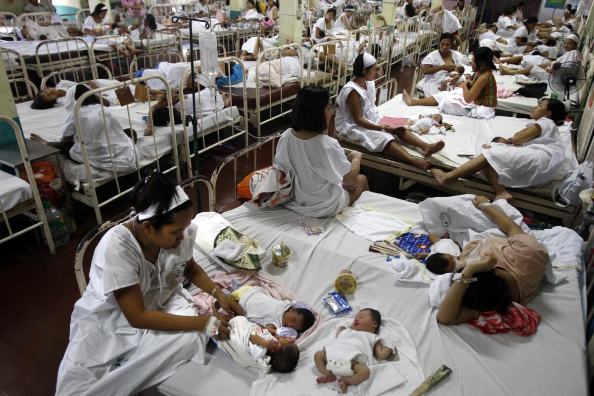 Even in the quiet season, women must share beds in the postnatal recovery room at Jose Fabella hospital.