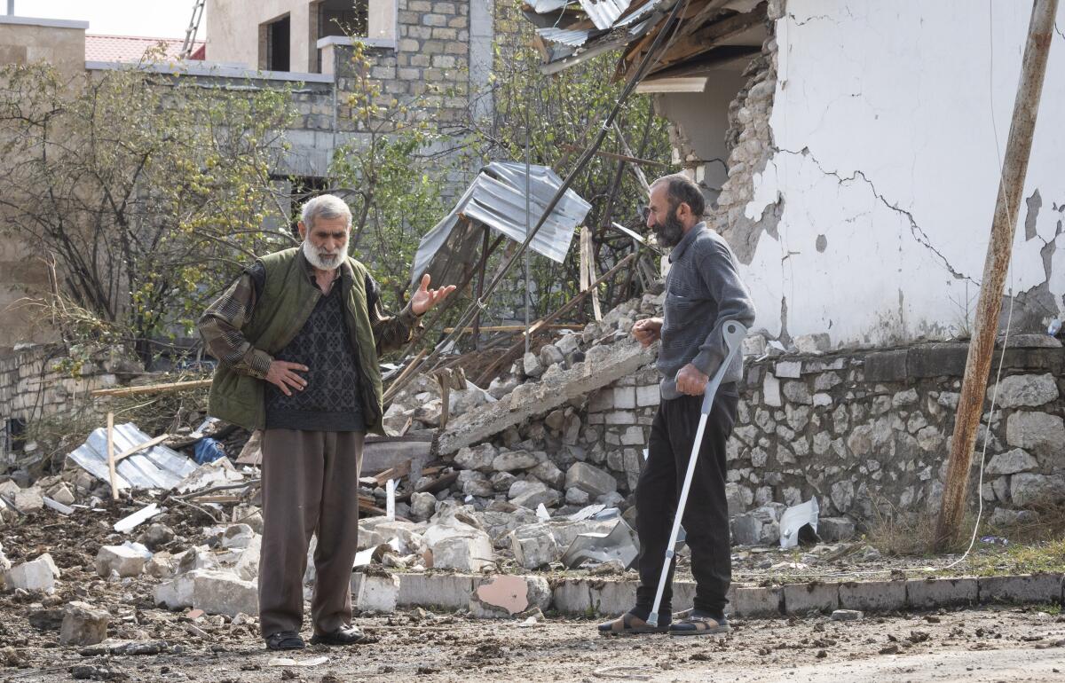 Men speak near a house destroyed by shelling in Nagorno-Karabakh.