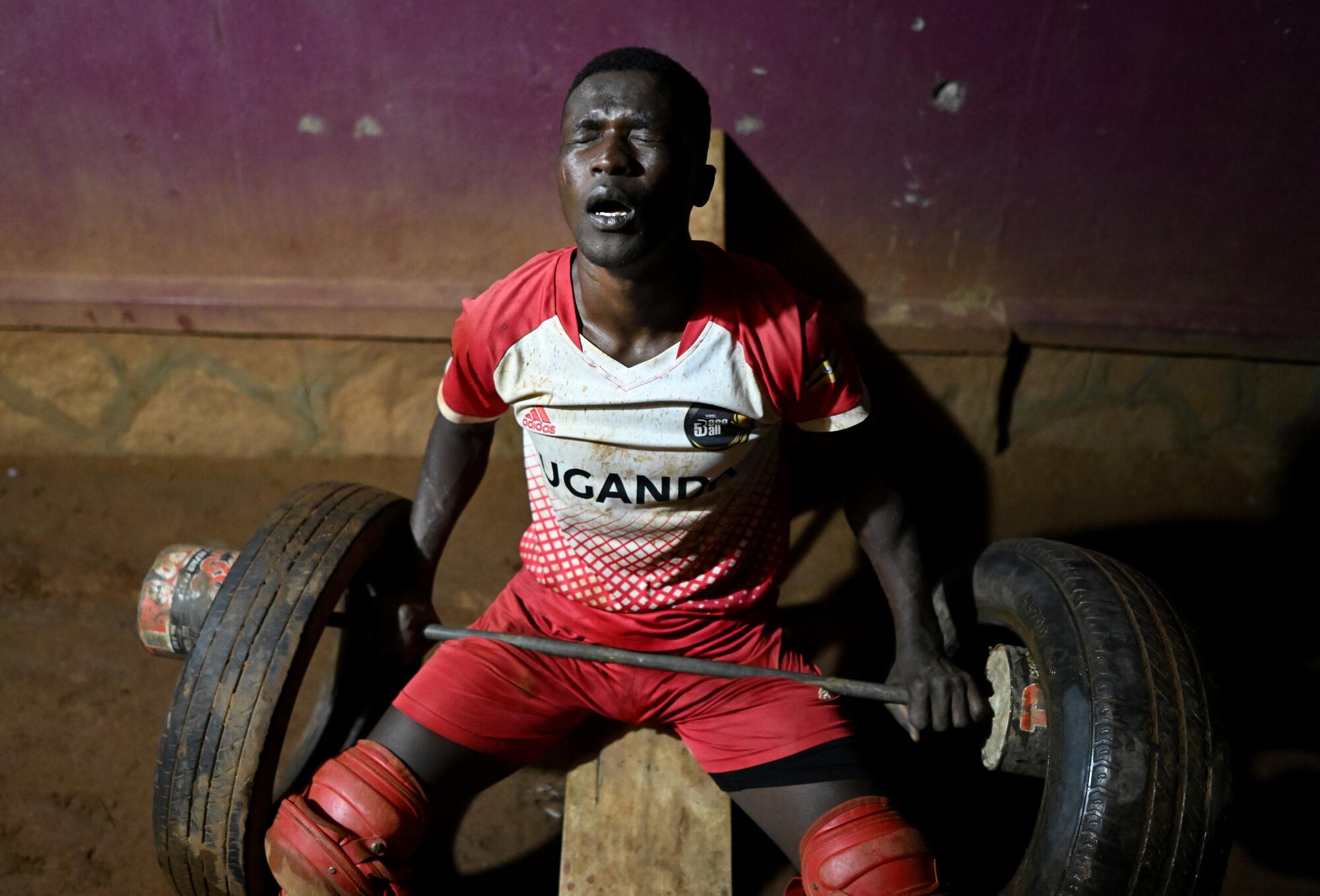 After having one meal for the day, an exhausted Dennis Kazumba works out late at night with old tires outside his home.