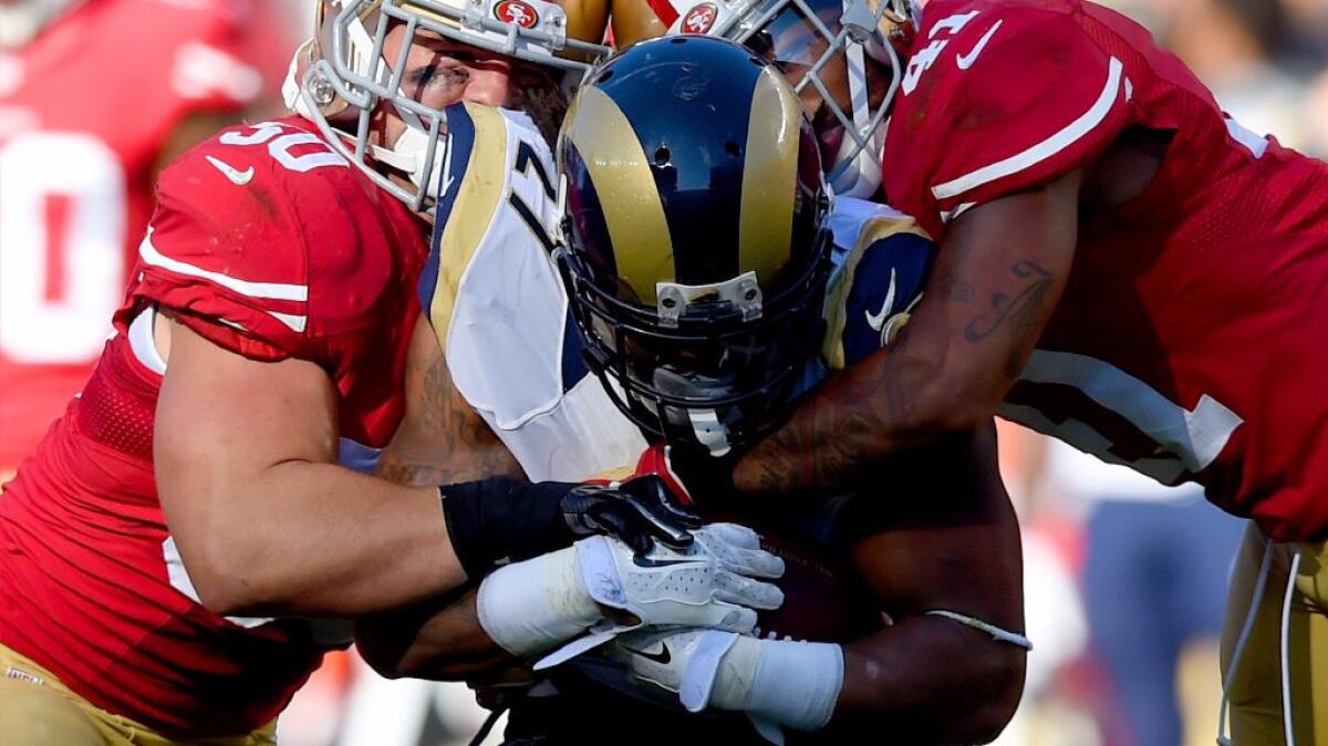 Rams running back Tre Mason is tackled by a pair of San Francisco 49ers during a game on Nov. 2, 2014.