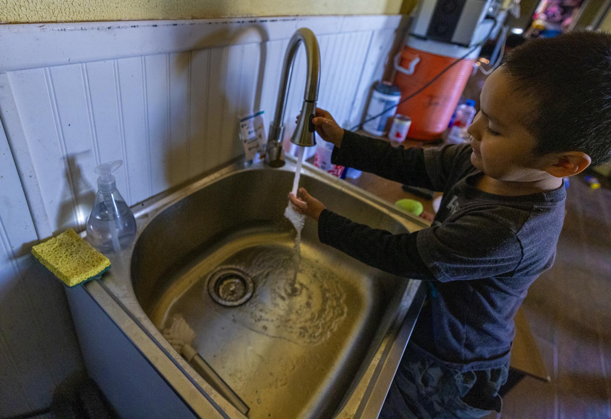 4 岁的亚历克斯·埃西蒂 (Alex Etsitty) 在纳瓦霍族的家中洗手。