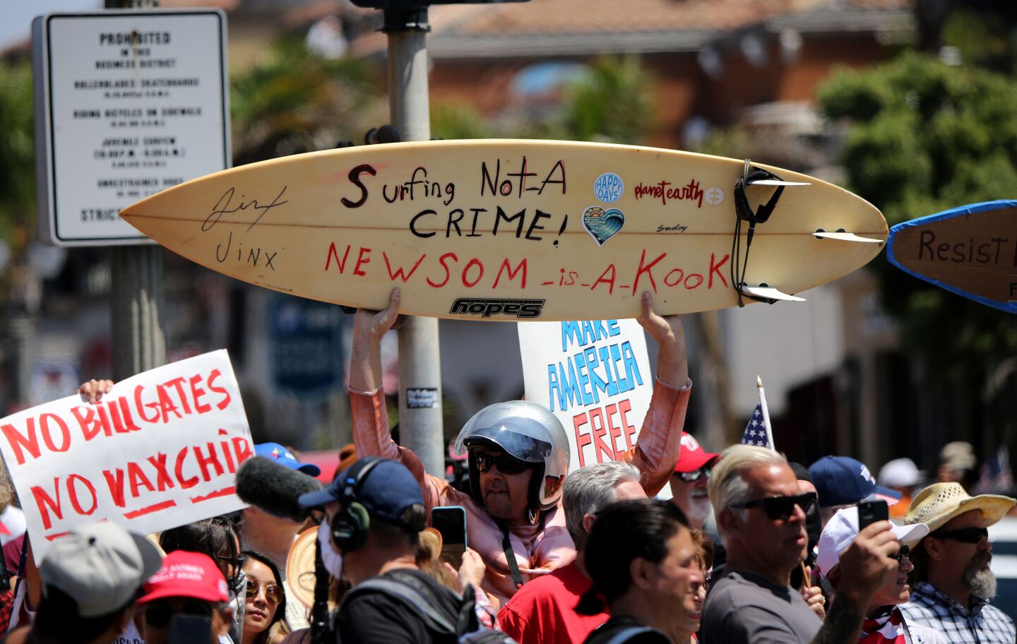 Protesters hold signs up during the protest in Huntington Beach on Friday.