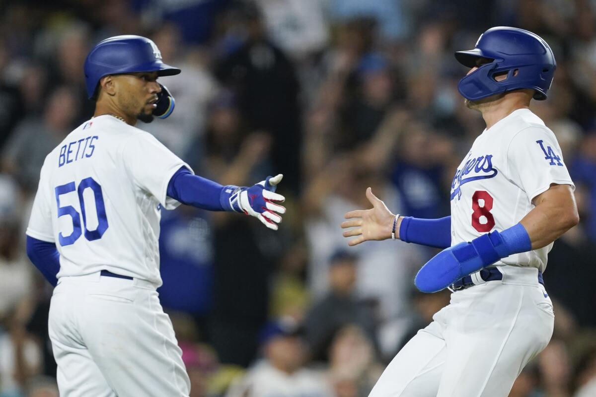 Dodgers' Kiké Hernández is congratulated by Mookie Betts after scoring against the Milwaukee Brewers.