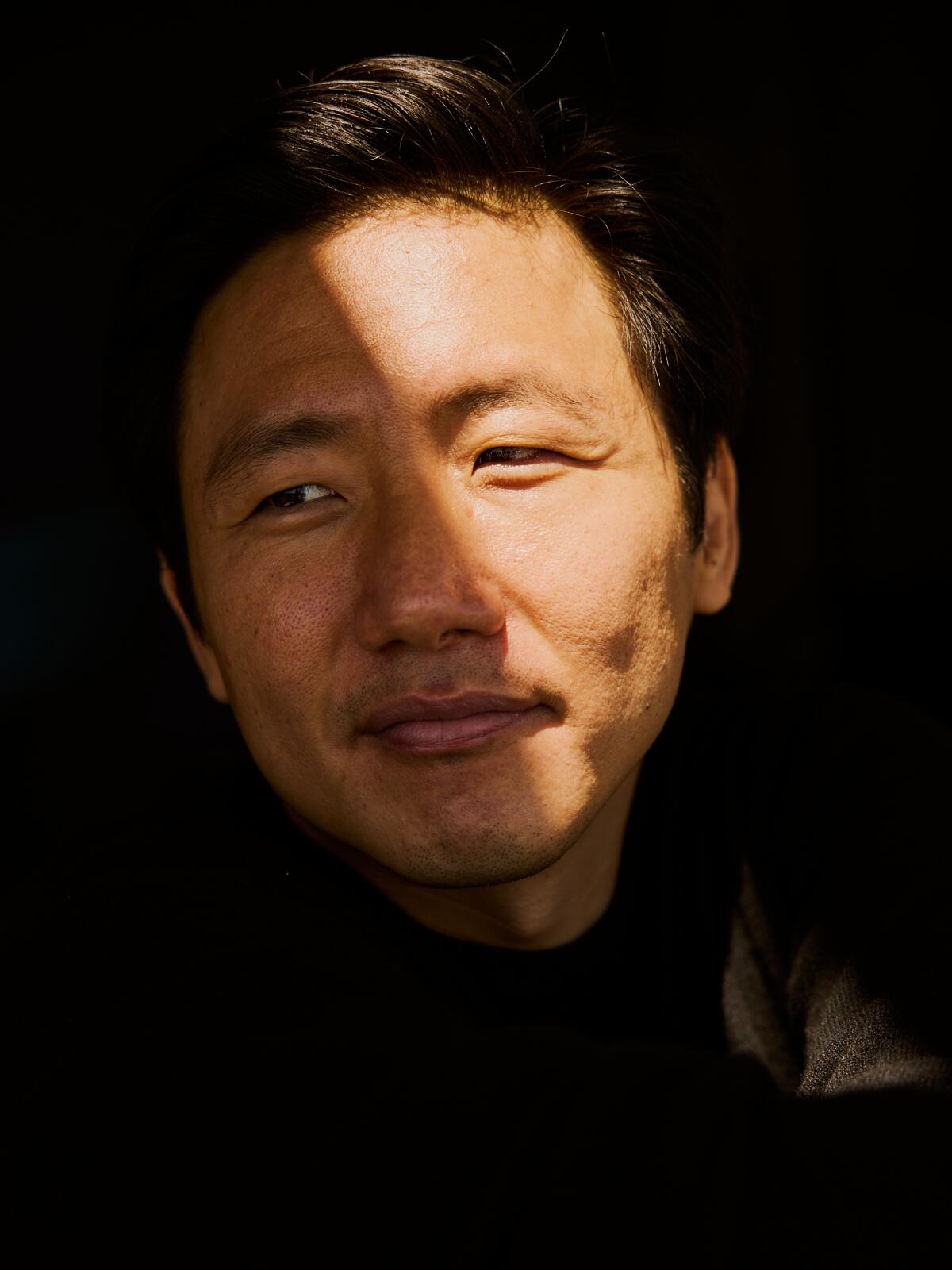 Hiro Murai smiles and looks to the side for a portrait.