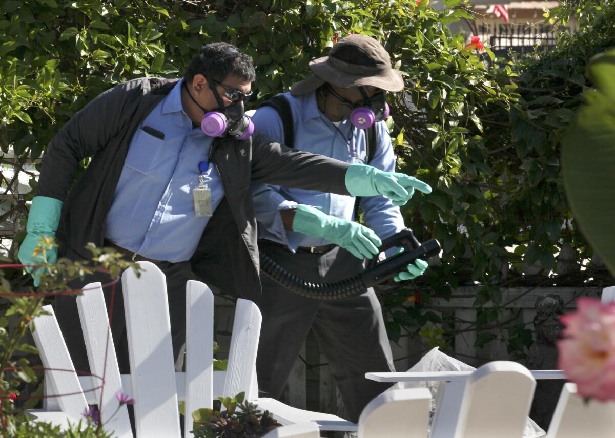 Ray Rivera, un trabajador de la agencia de salud del Condado de San Diego indica a Sean Simmons, otro empleado, donde rociar con insecticida en el exterior de una casa en Nestor, cerca de la interestatal 5.
