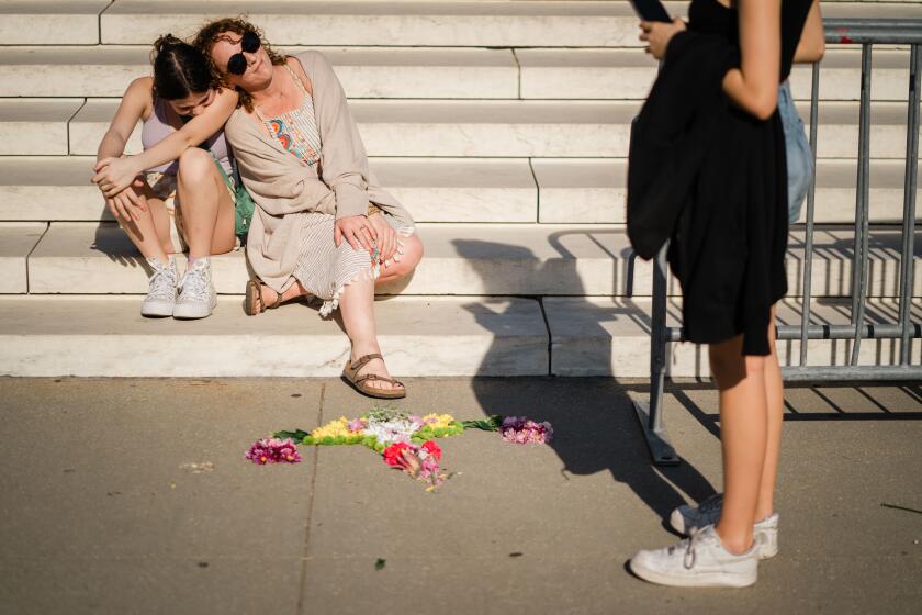 WASHINGTON, DC - APRIL 21: Krissy Shields leans against her daughter after assembling flower art, "Reproductive Justice for Every Damn Body," at the base of the steps of the Supreme Court of the United States on Friday, April 21, 2023 in Washington, DC. The High Court is expected to decide by Friday night whether to grant the Biden administration's emergency request to maintain the Federal Drug Administration's (FDA) approval of mifepristone, after a lower court limited the availability of the drug while an appeal moves forward. (Kent Nishimura / Los Angeles Times)