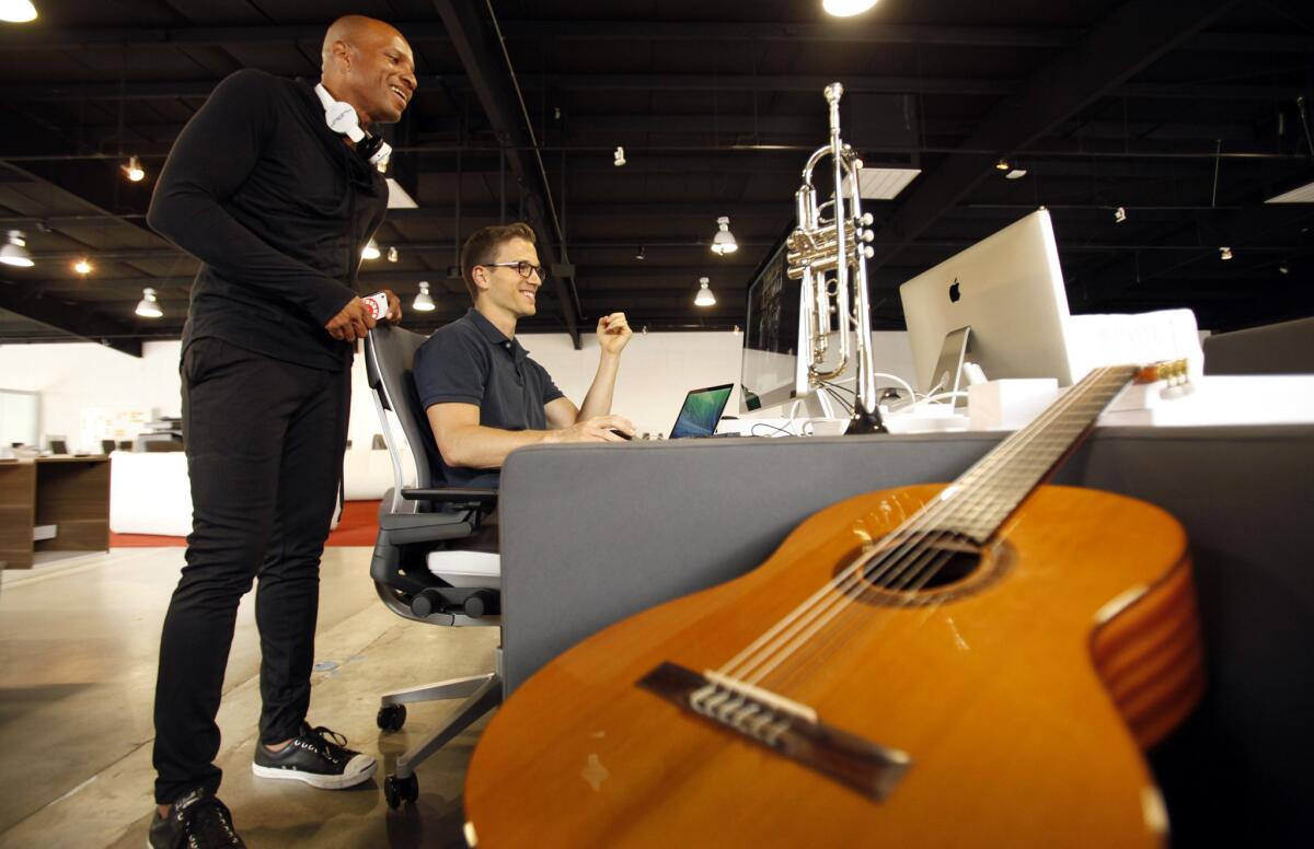 Flipagram's George Snarberg, right, and Phoenix Normand, left, sort through photo albums as instruments sit nearby.