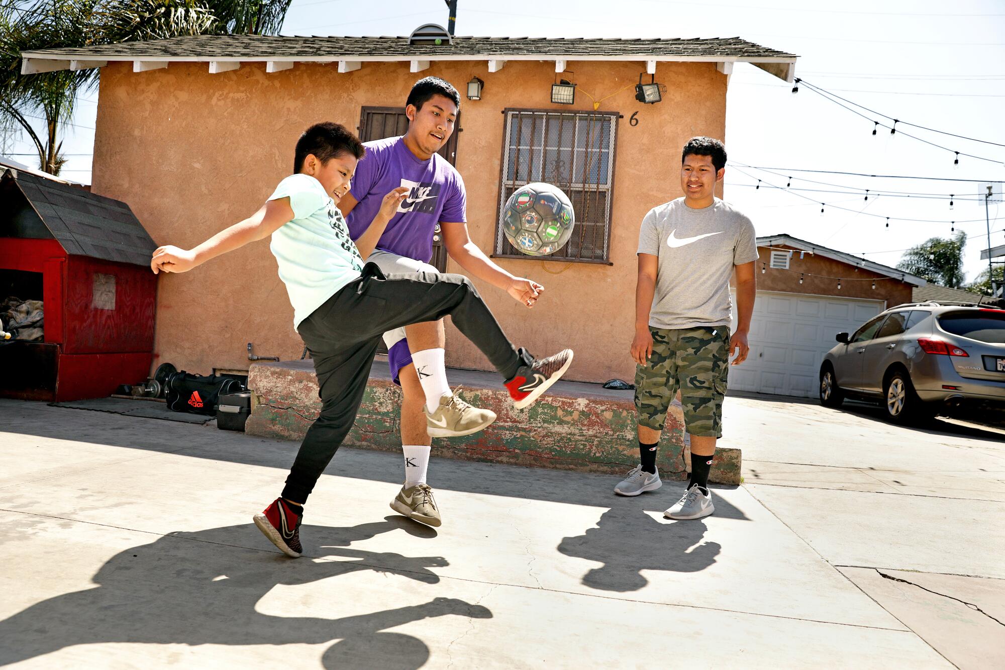 Julio Flores, right, plays soccer with his brothers Angel and David after school at home