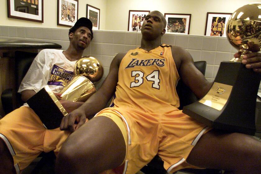 Lakers stars Kobe Bryant, left, and Shaquille O'Neal hold the championship trophies after winning Game 6 of the 2000 NBA Finals against the Indiana Pacers.