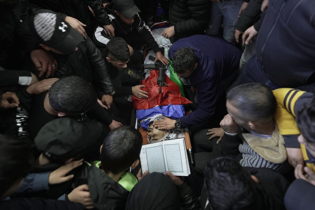 Palestinians mourn around the body of Bakir Muhammad Musa Hashash, 21, who was killed by Israeli fire, during his funeral in Balata refugee camp near the West Bank town of Nablus, Thursday, Jan. 6, 2022. The Israeli military said its forces shot and killed Hashash, a Palestinian who had opened fire on them during an arrest raid in the West Bank early Thursday. (AP Photo/Majdi Mohammed)