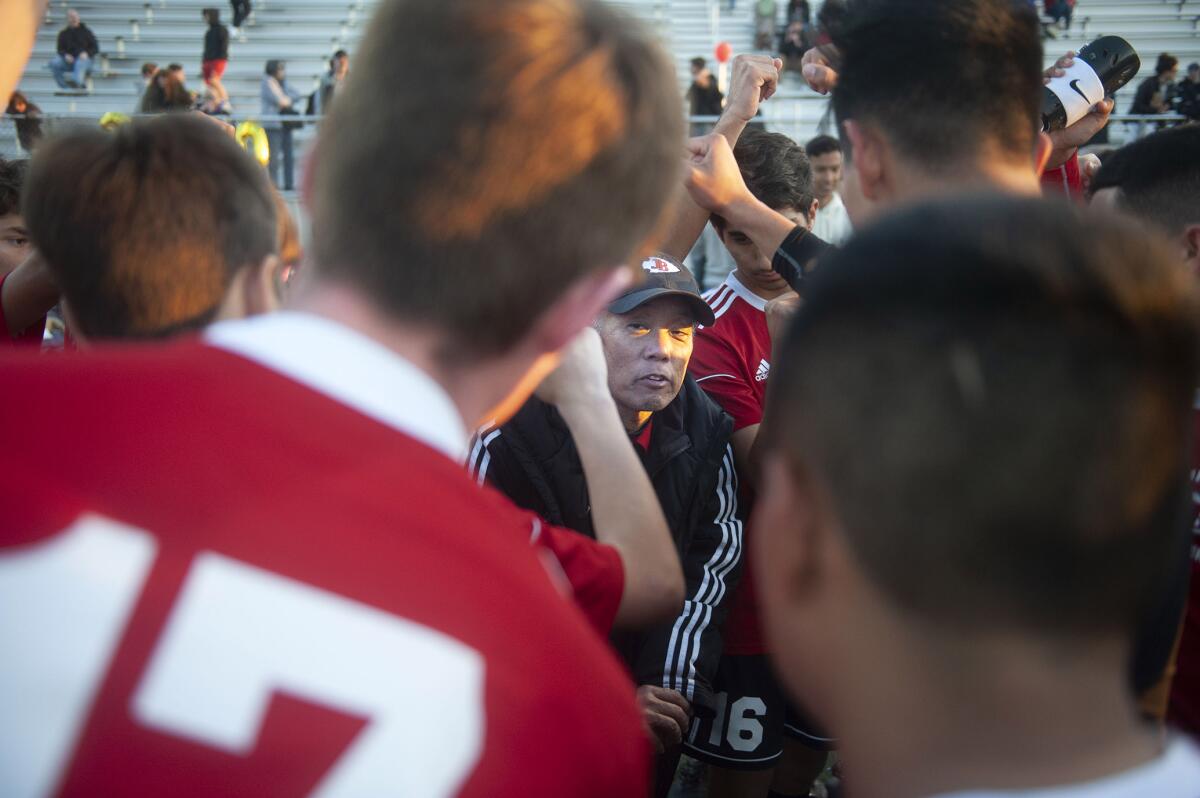 Former Burroughs High boys soccer coach Mike Kodama is surrounded by players at the conclusion of Thursday's game against Burbank. (Photo by Miguel Vasconcellos)