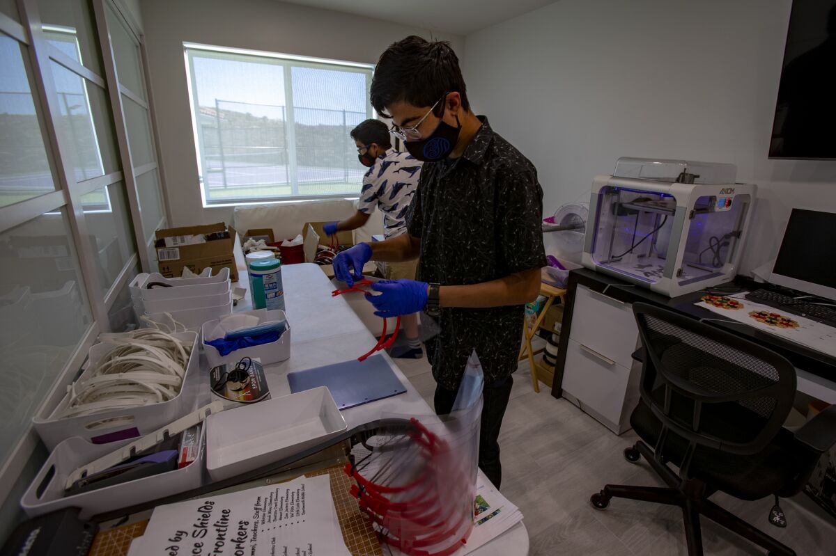 Zubin Carvalho, front and his brother Tenzing put together face shields that they've made using a 3-D printer in their home.