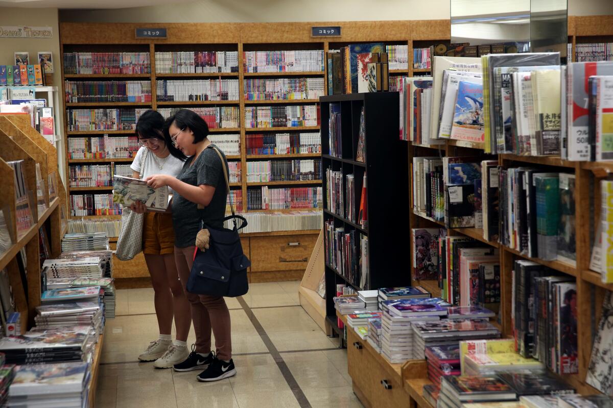 Two people look at a book in a bookstore