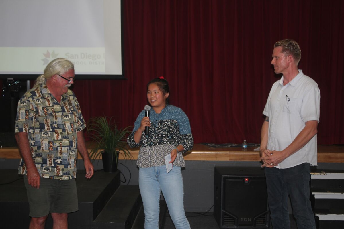During the July 17 PB Town Council Meeting at Crown Point Jr. Music Academy, Council member Karl Jaedtke (left) announces that Mission Bay High School senior Xiu Mei Golden is the winner of this year’s Dan Froelich Youth Award for outstanding community service. Town Council president Brian White presents a $1,000 check to Golden, who gives an impromptu acceptance speech.