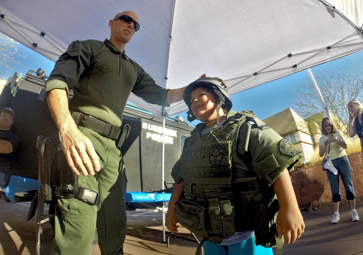 Burbank SWAT officer Adam Cornils helps 6-year-old Jacob Bame try on some gear at Burbank's National Night Out at police headquarters in Burbank on Tuesday, Aug. 5, 2014.