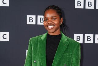 A young Black woman with braided hair in a bright green velvet suit and a black shirt smiling against a BBC backdrop
