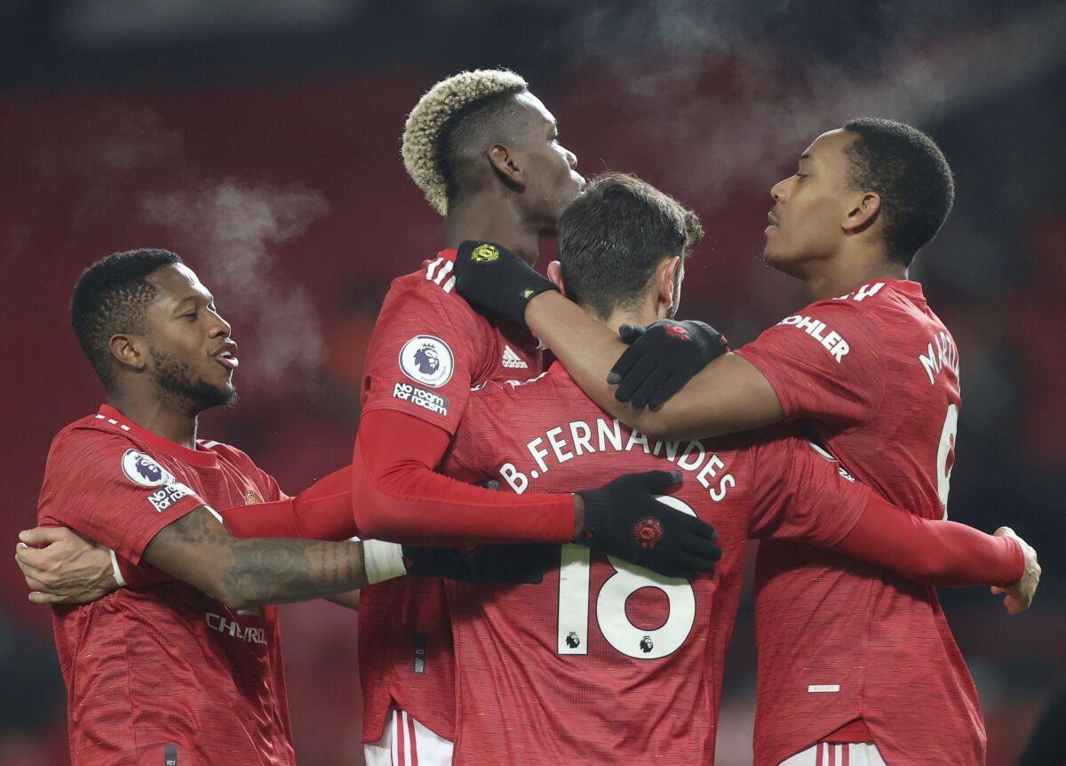 Manchester United's Bruno Fernandes, (18), celebrates with teammates after scoring his sides 2nd goal of the game from the penalty spot during the English Premier League soccer match between Manchester United and Aston Villa at Old Trafford in Manchester, England, Friday, Jan. 1, 2021. (Carl Recine/ Pool via AP)