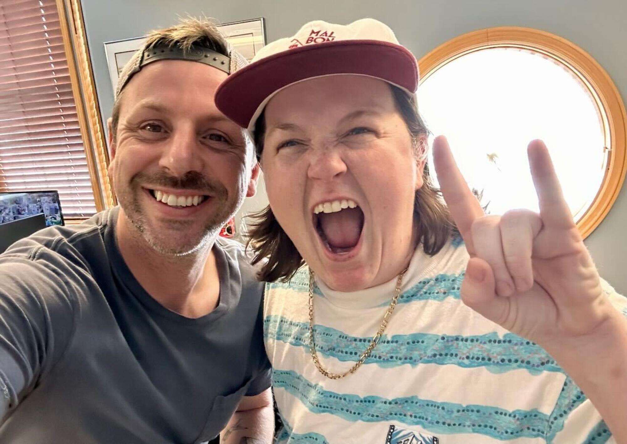 a man and a woman smile at the camera, goofy, selfie-style