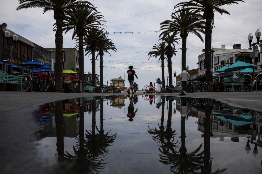 HERMOSA BEACH-CA-JULY 26, 2021: A pedestrian is reflected in a puddle in Hermosa Beach on Monday, July 26, 2021. (Christina House / Los Angeles Times)