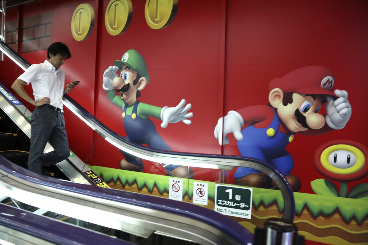 Un cliente pasa por delante de un pared decorada con los personajes del videojuego Super Mario de Nintendo, en una tienda en Tokio, el 13 de julio de 2015. (Foto AP/Koji Sasahara)