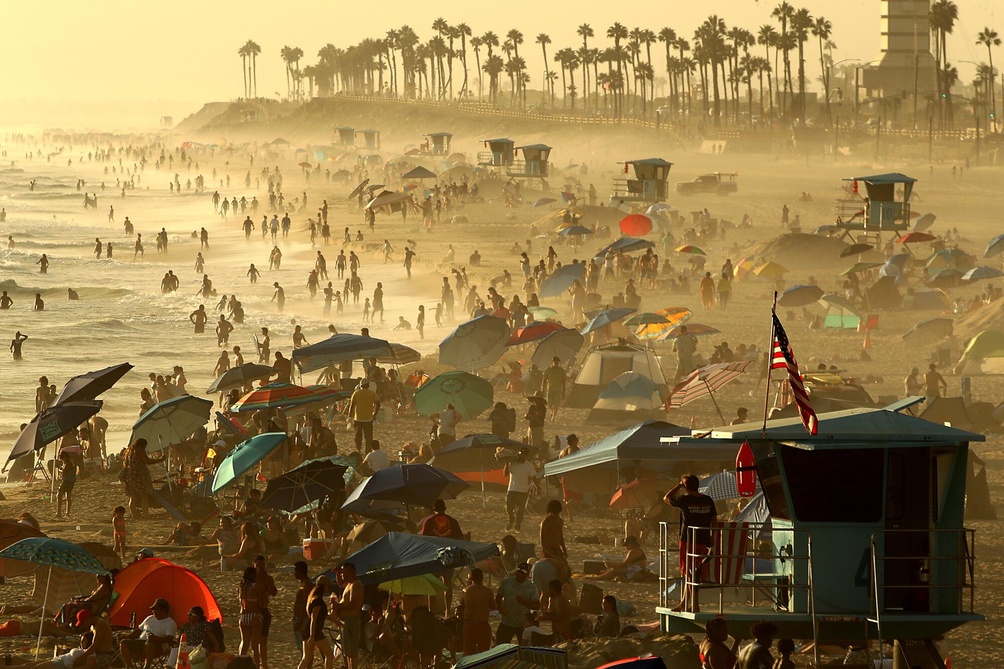 People crowd the beach as fog drifts ashore at sunset at Huntington Beach on Monday.