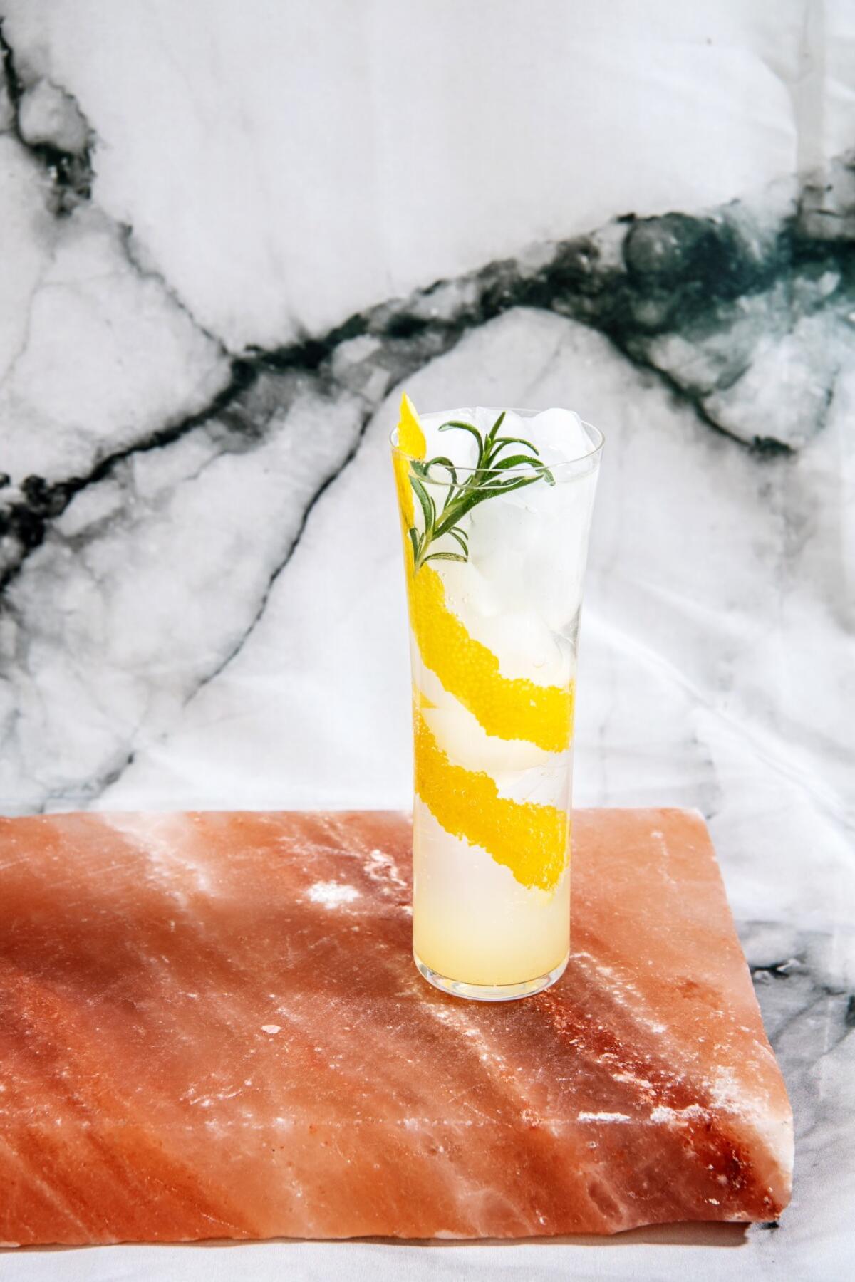 Yuzu Spritzer in a tall glass garnished with a swath of lemon zest and a rosemary sprig