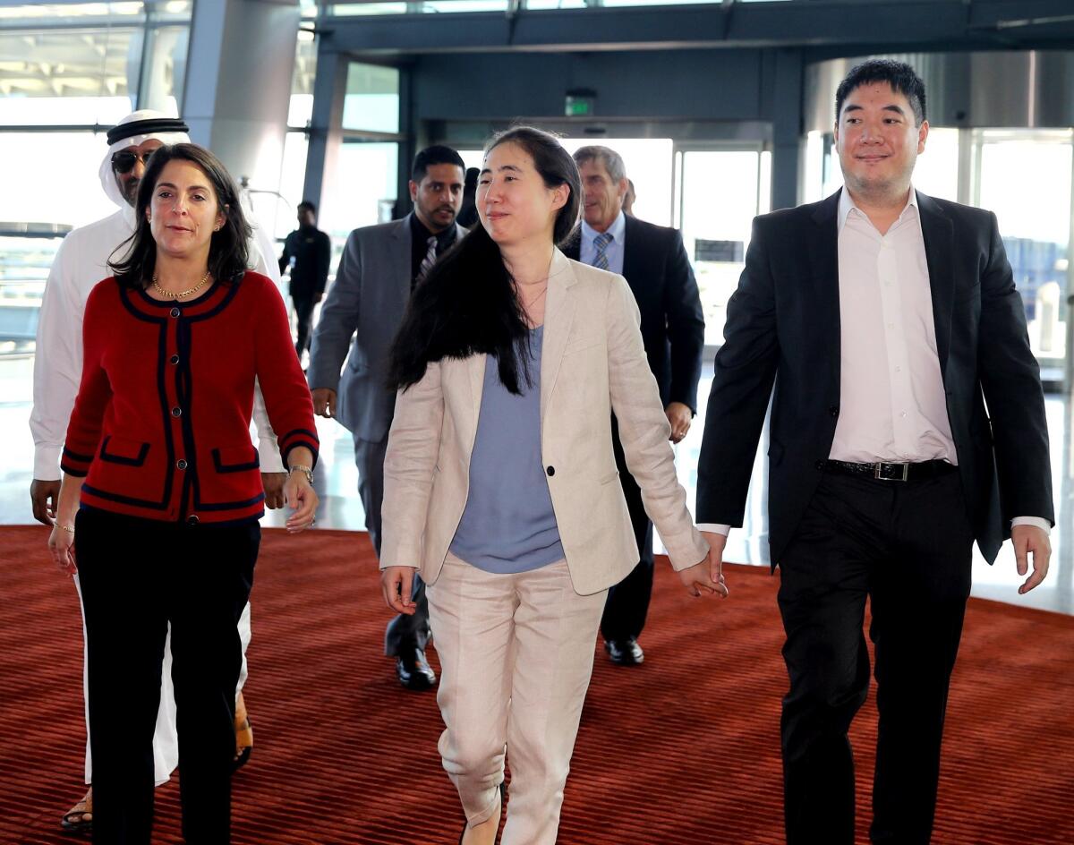 Escorted by U.S. Ambassador to Qatar Dana Shell Smith, left, Grace and Matthew Huang walk to their departure gate at Hamad International Airport in Doha on Wednesday.