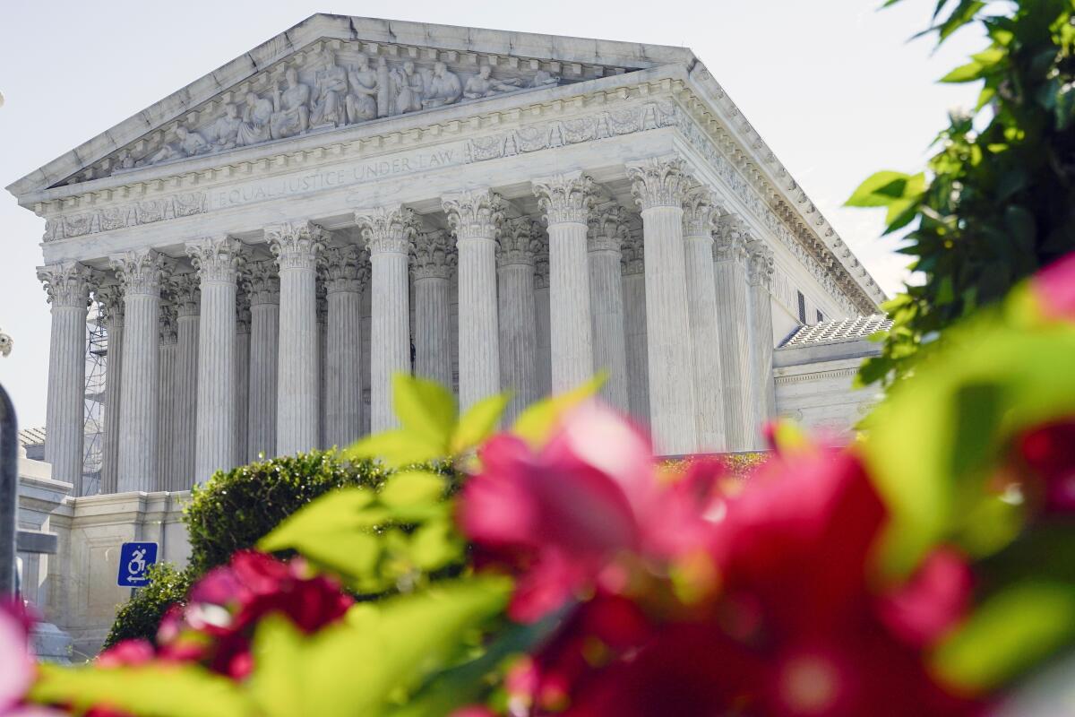 The U.S. Supreme Court exterior in Washington with red flowers in the foreground. 