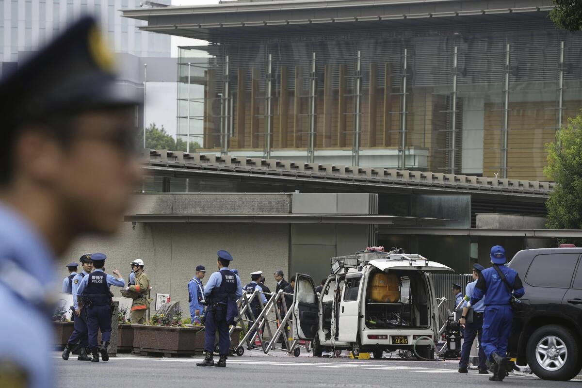 Police officers work near a vehicle that hit a barricade near the prime minister's office in Tokyo.