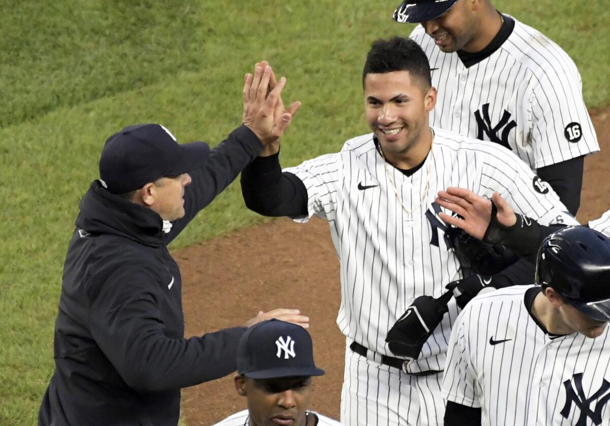 New York Yankees' Gleyber Torres is congratulated by manager Aaron Boone after Torres drove in the winning run in the 11th inning of the team's baseball game against the Washington Nationals on Saturday, May 8, 2021, at Yankee Stadium in New York. The Yankees won 4-3. (AP Photo/Bill Kostroun)
